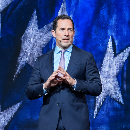Dave Grimaldi, CEO of the Direct Selling Association, speaking before an American flag backdrop